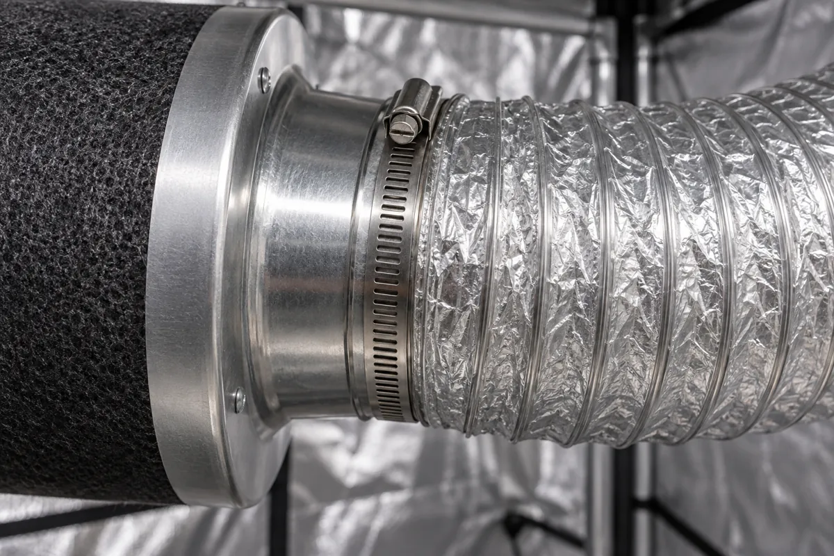 Unión entre la boca de un filtro de carbón y un ducto flexible de aluminio, sellada con una abrazadera metálica