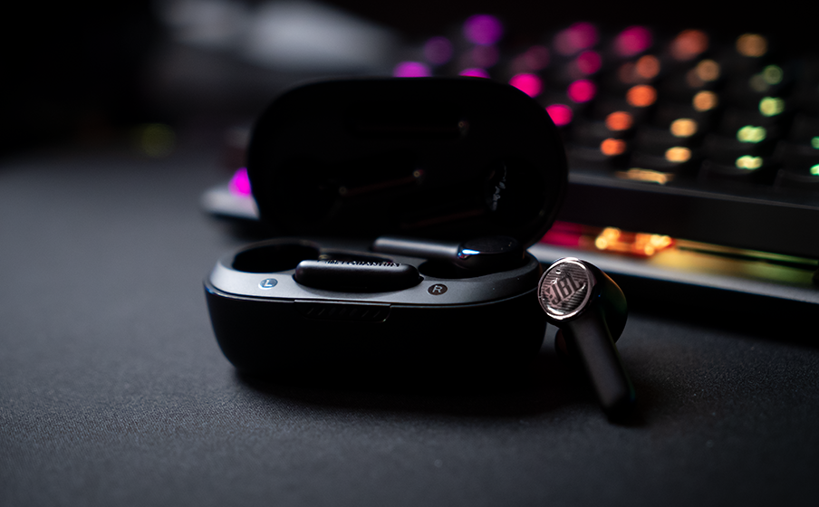 JBL Quantum TWS con estuche de carga sobre escritorio Gamer con iluminación RGB