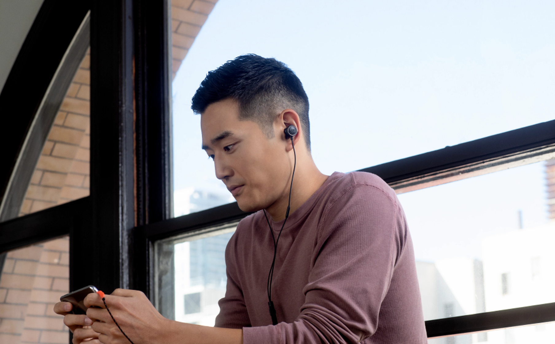 Usuario jugando en un smartphone con audífonos JBL Quantum 50